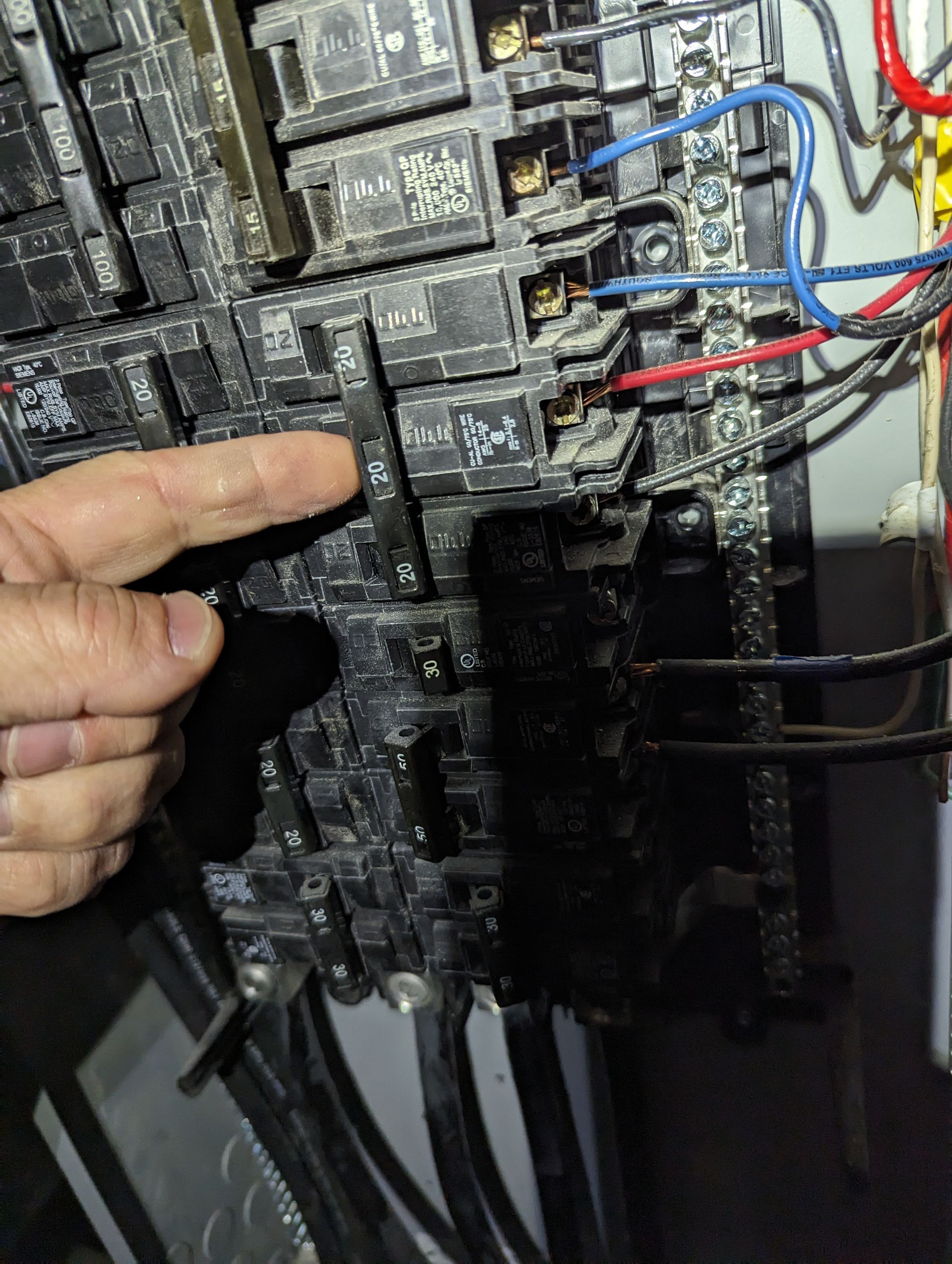 Technician inspecting an electrical control panel with a manual