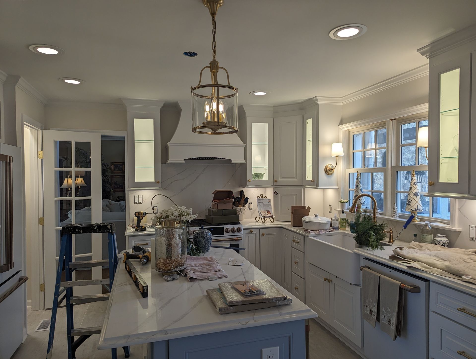 Bright white kitchen with island, range hood, and gold pendant light.