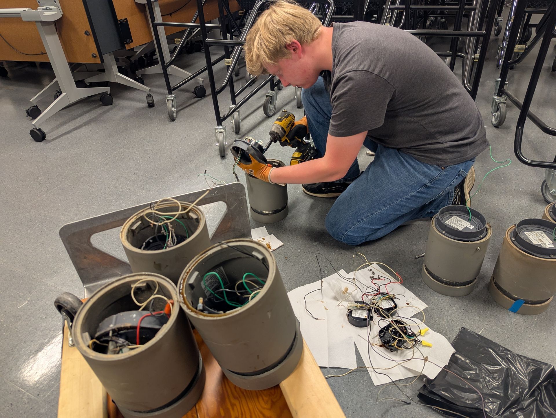 Two people shaking hands in a bright, unfinished room, with one holding a tablet and wearing a tool belt.