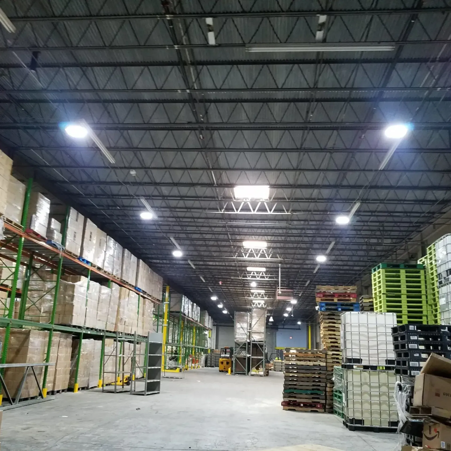 Warehouse interior with tall shelving, stacked pallets, and bright overhead lights