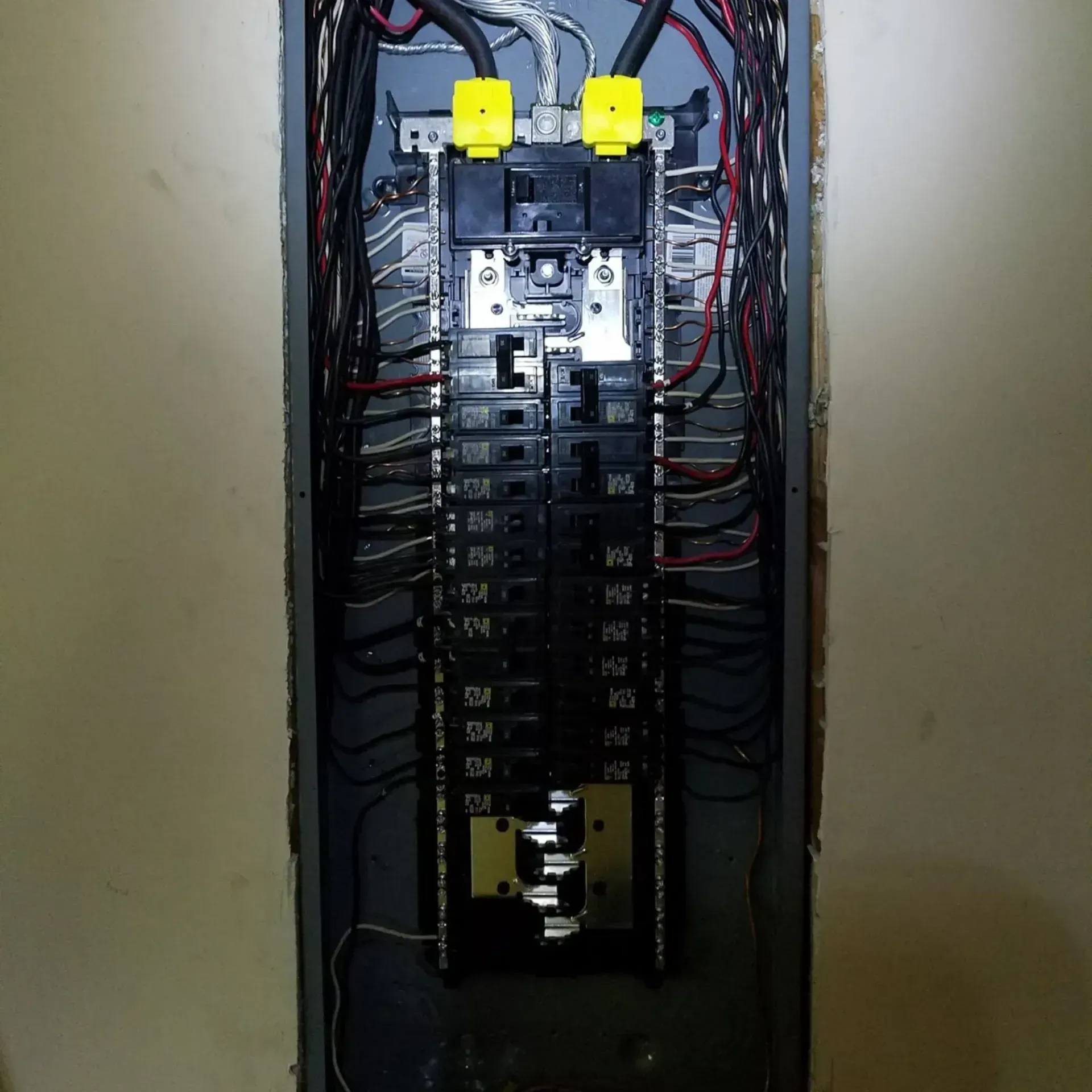 Electrical panel with rows of black circuit breakers and wiring