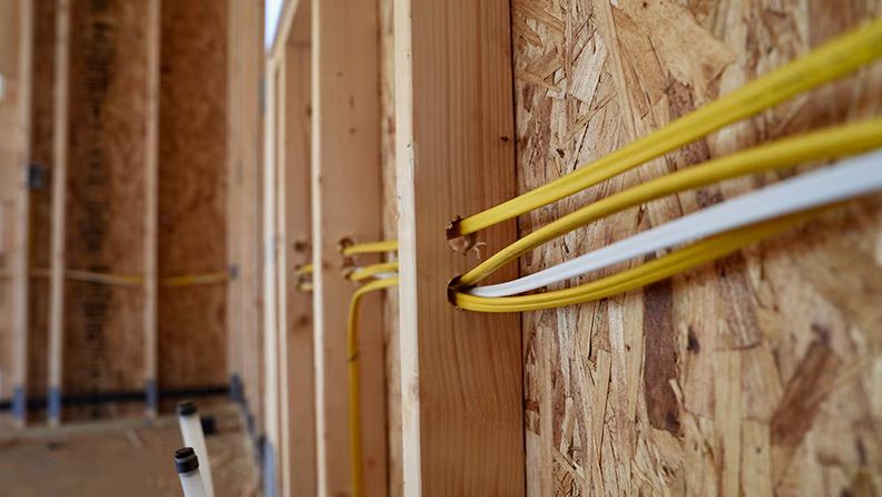 Opening in floor with tools and a black box. Carpet and white walls surround the area.