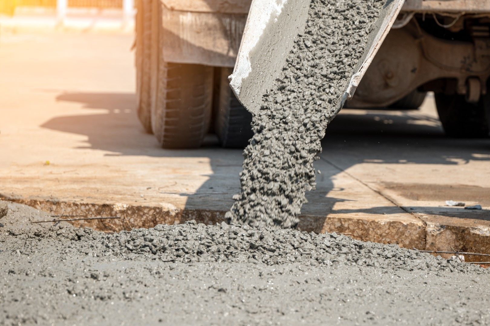 Concrete being poured from a truck onto a surface, creating a construction site.