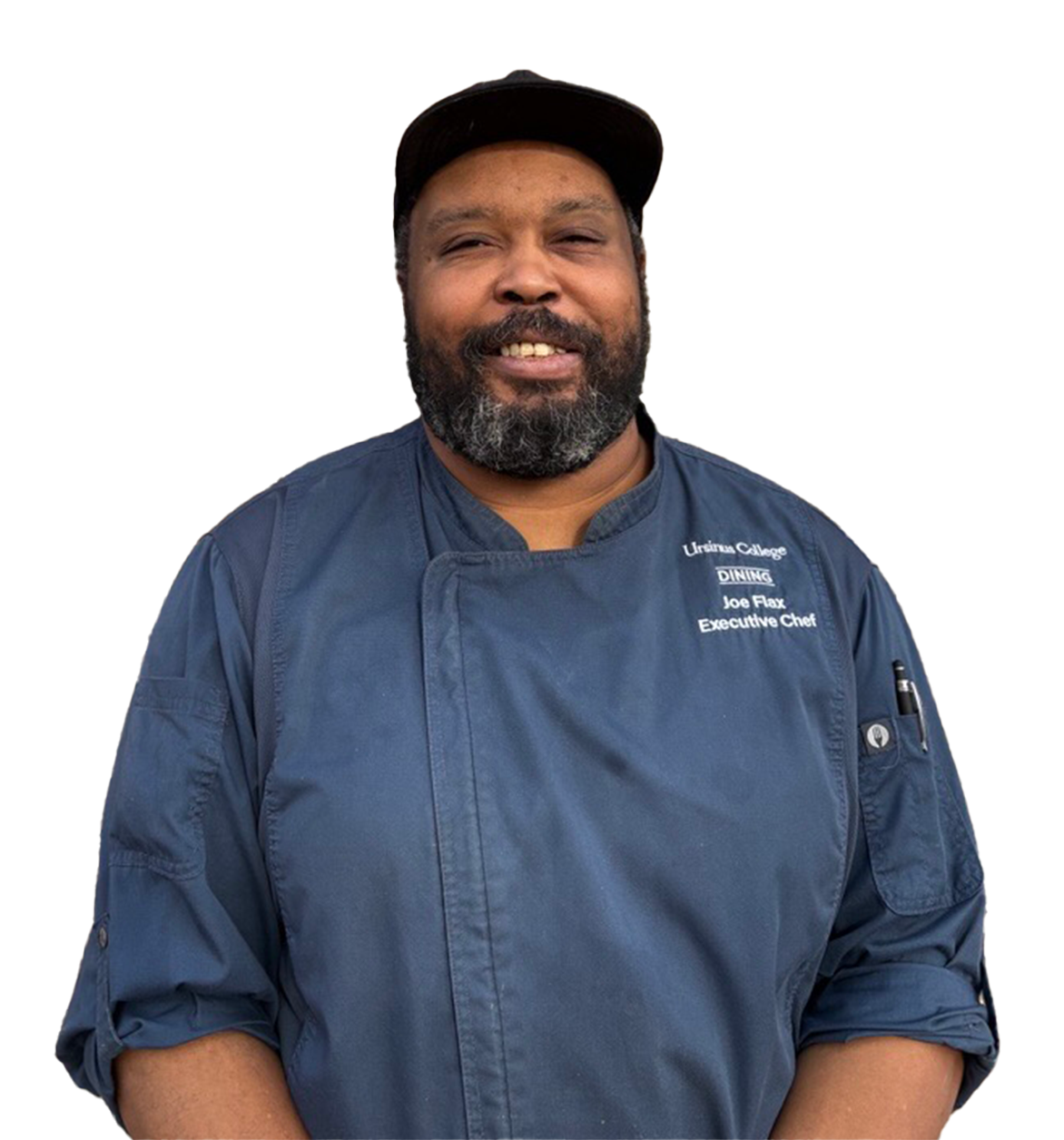 Chef Joe Flax, wearing a cap and chef coat, smiles.