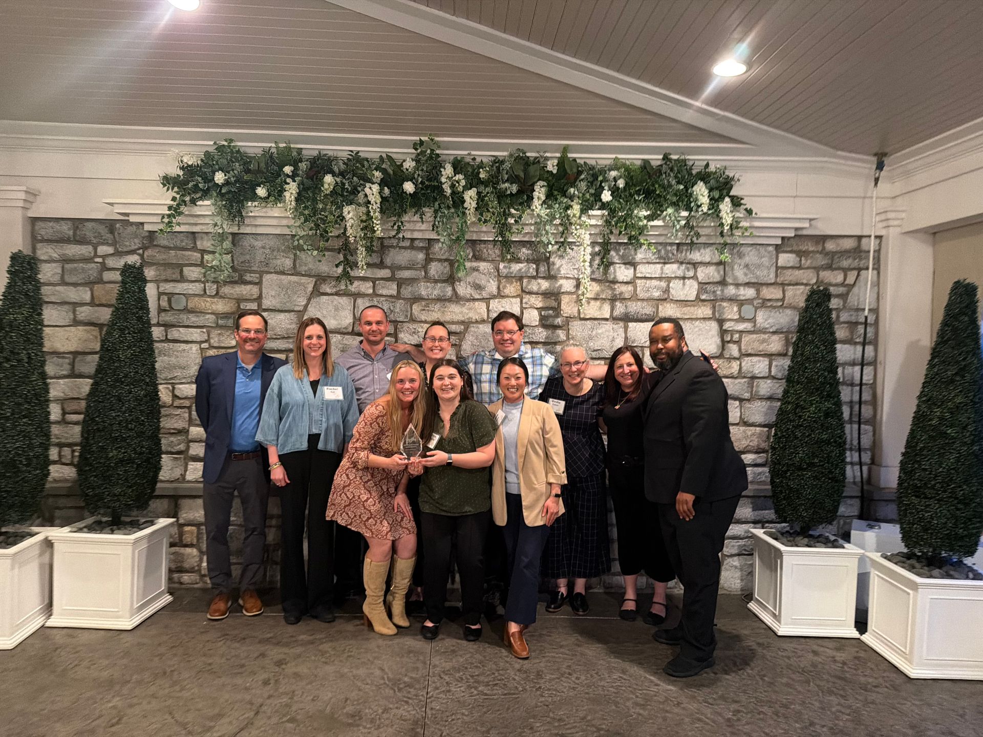 Group of dining staff smiling behind a table that says 