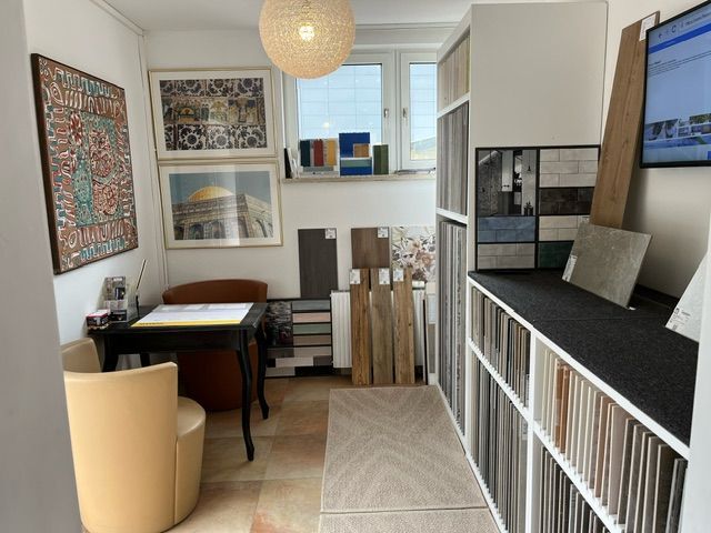 Ein Zimmer mit einem Schreibtisch und Stühlen und einem Fernseher an der Wand