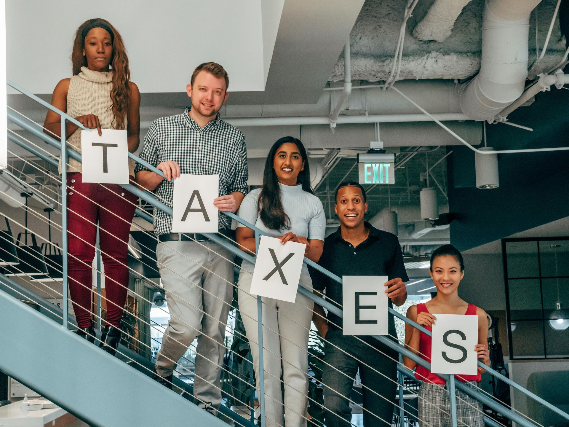 A group of people are standing on a set of stairs holding signs that say taxes.