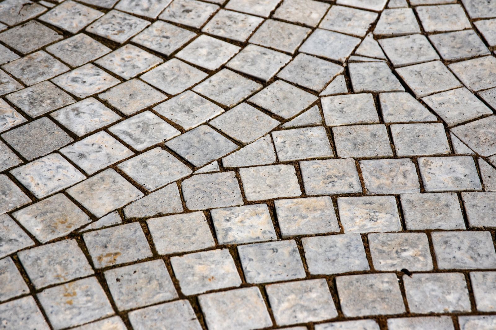 Close-up of gray, square paving stones in a curved, textured pattern.