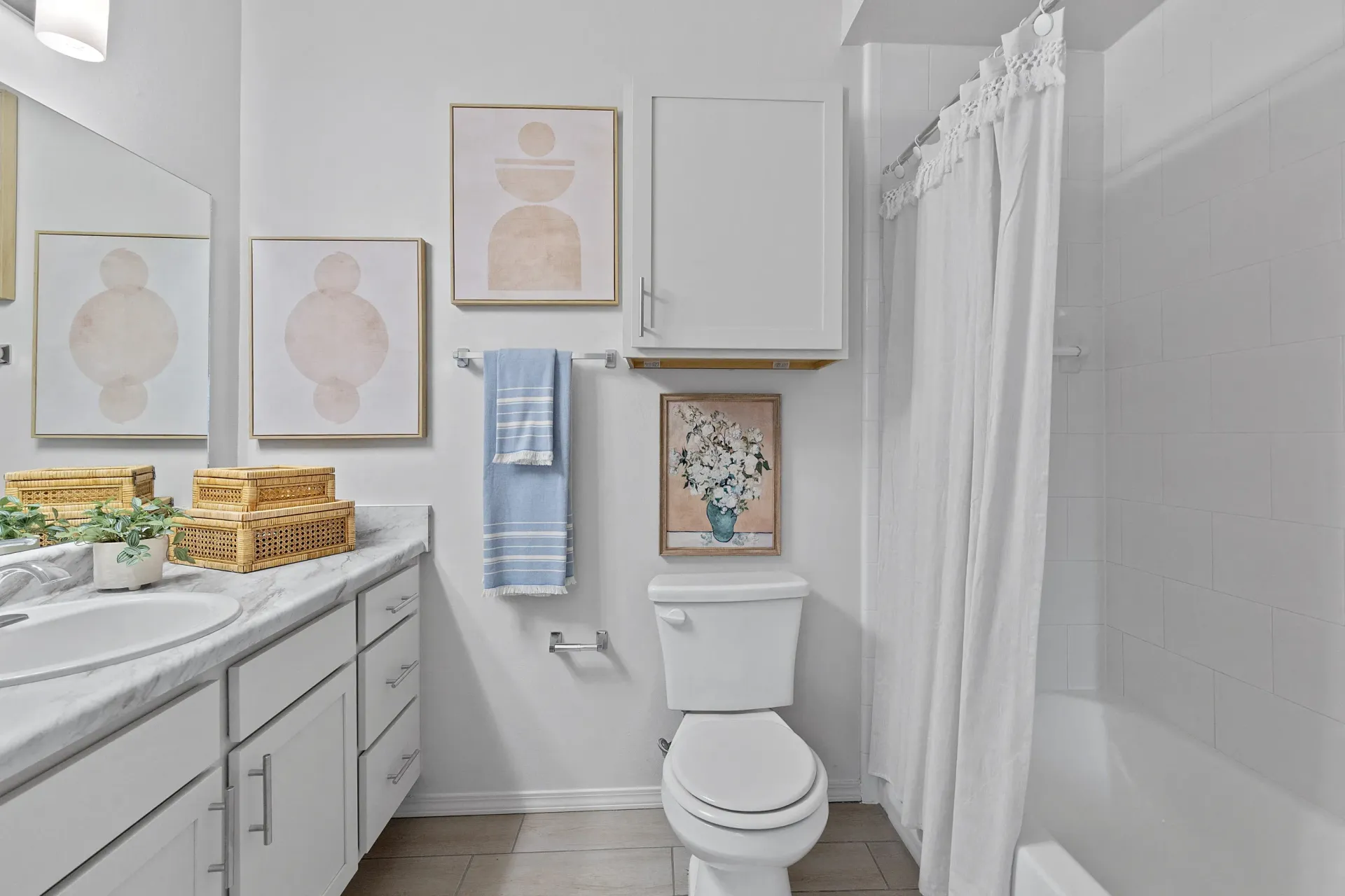 Modern bathroom with white cabinetry, decorative art, and plants.