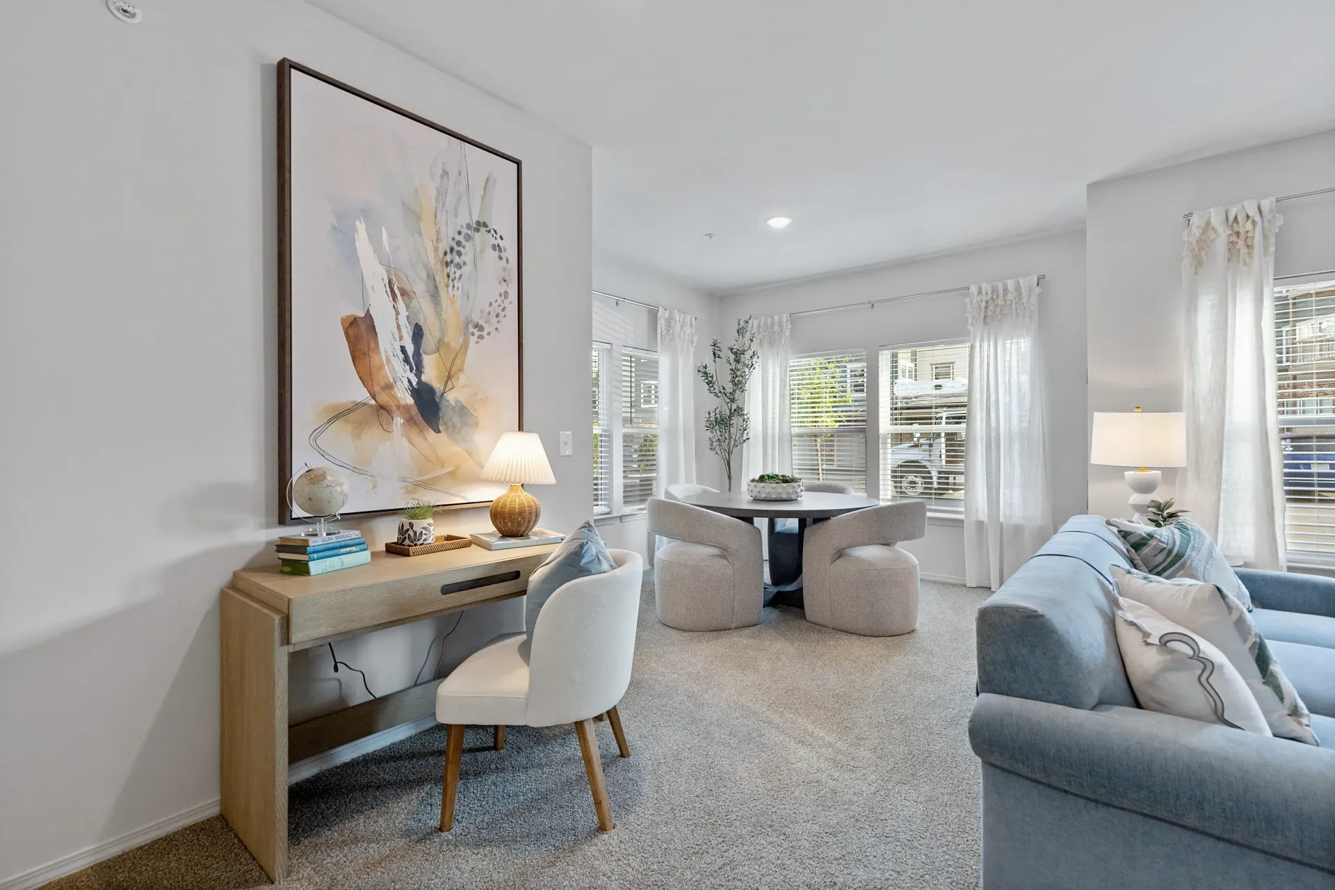 Cozy apartment living space with desk, modern furniture, and large windows.