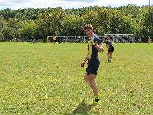 A man is standing in the middle of a soccer field.