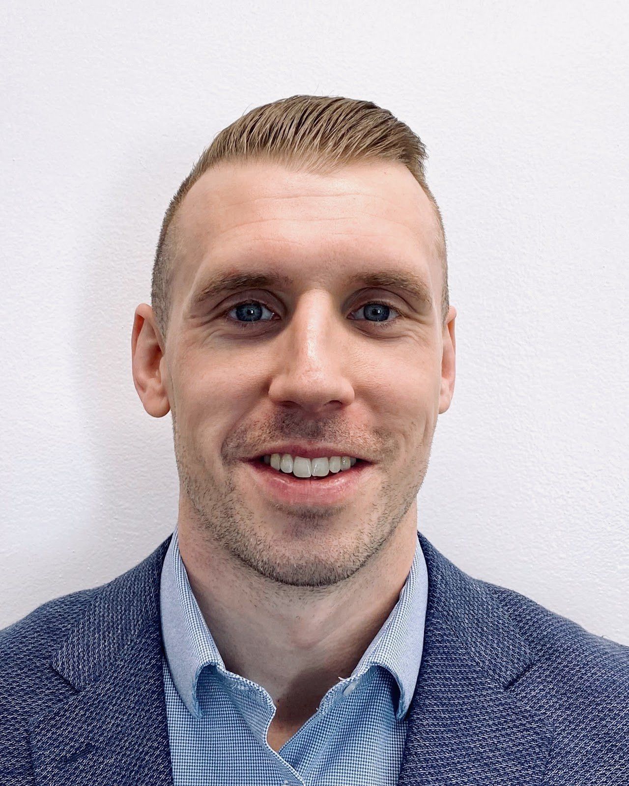 A man in a suit and blue shirt is smiling for the camera.