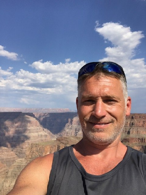 A man is taking a selfie in front of a canyon.