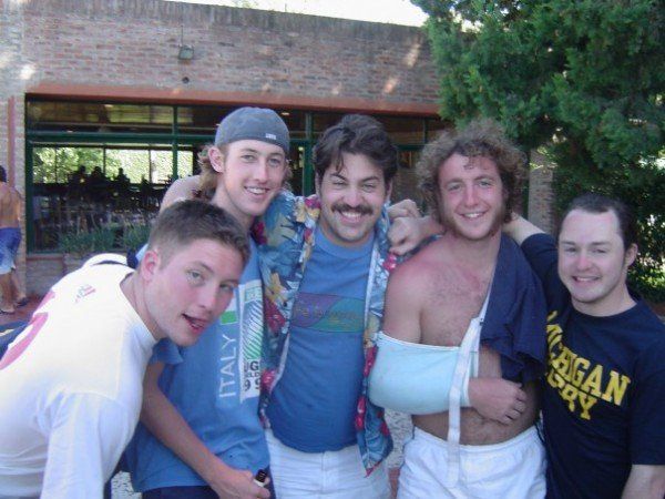 A group of young men posing for a picture with one wearing a shirt that says american rugby