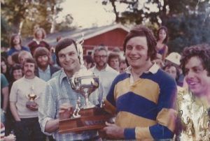 Two men are holding a trophy in front of a crowd.