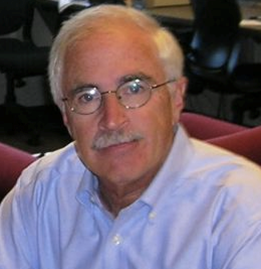 A man with glasses and a mustache is wearing a blue shirt
