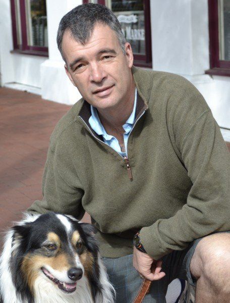 A man in a green sweater sits next to a dog