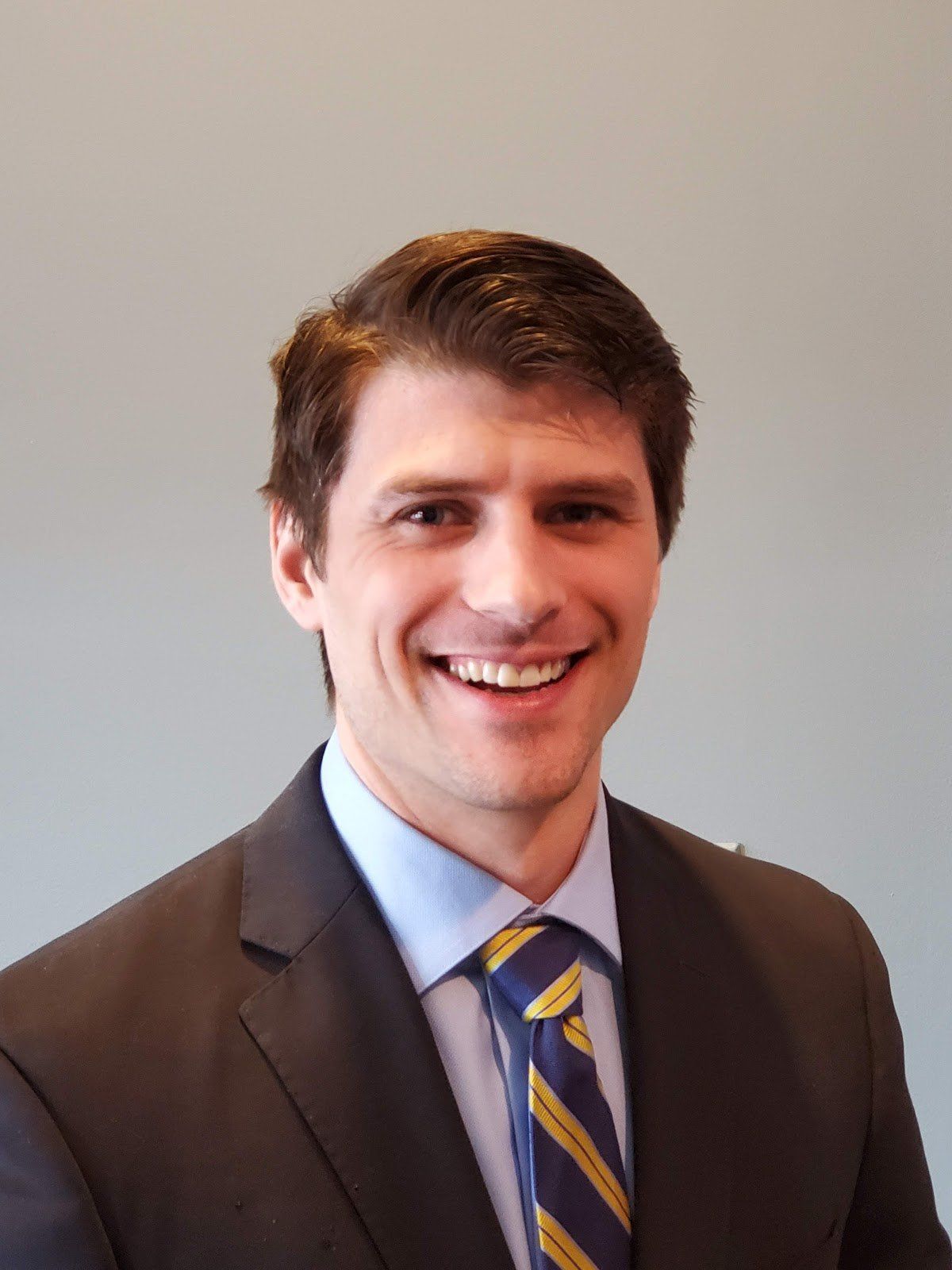 A man in a suit and tie is smiling for the camera