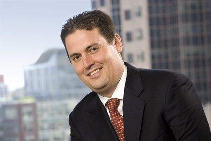 A man in a suit and tie is smiling for the camera