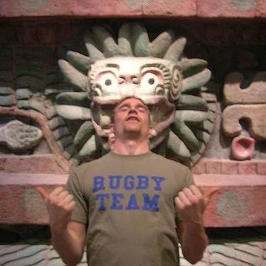 A man wearing a rugby team shirt stands in front of a statue