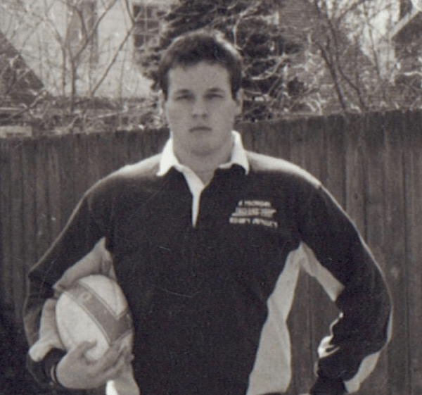 A man holding a rugby ball in a black and white photo