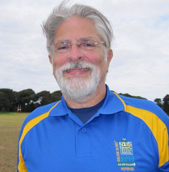A man with a beard and glasses is wearing a blue and yellow shirt