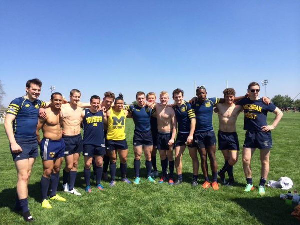 A group of rugby players are posing for a picture on a field.