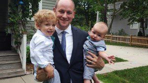 A man in a suit and tie is holding two babies in his arms.