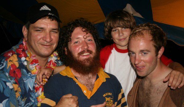 A group of men posing for a picture with one wearing a hawaiian shirt