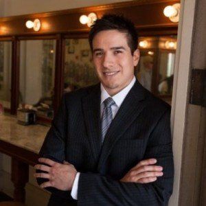 A man in a suit and tie is standing with his arms crossed