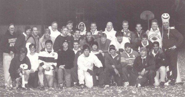 A group of people are posing for a picture and one of them is wearing a sweatshirt with the number 8 on it