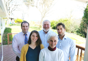 A group of people are posing for a picture on a porch.