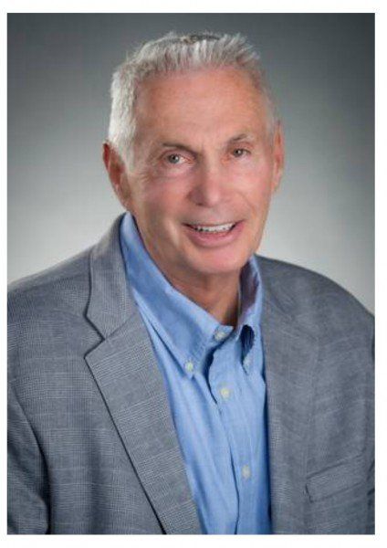 A man in a suit and blue shirt is smiling for the camera