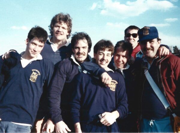 A group of men are posing for a picture and one of their shirts says ucsd
