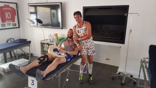 A man in a dress is standing next to a man in a hospital bed.