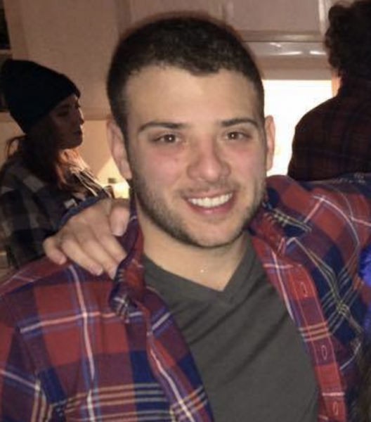 A man in a plaid shirt has his arm around another man 's shoulder