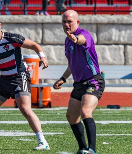 A man in a purple shirt is running on a field