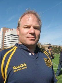 A man wearing a kooga shirt stands in a field