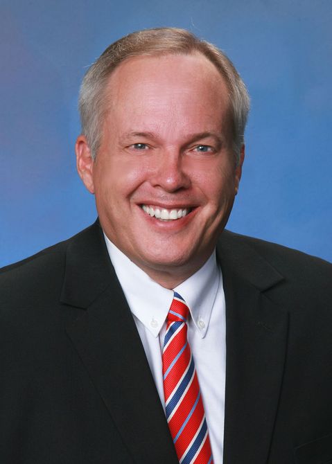 A man in a suit and tie is smiling for the camera