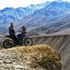 A man is riding a motorcycle on a dirt road in the mountains.