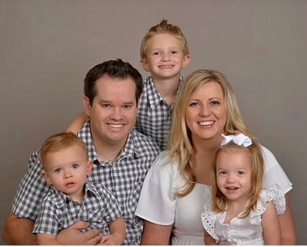 A family is posing for a picture together and smiling for the camera.