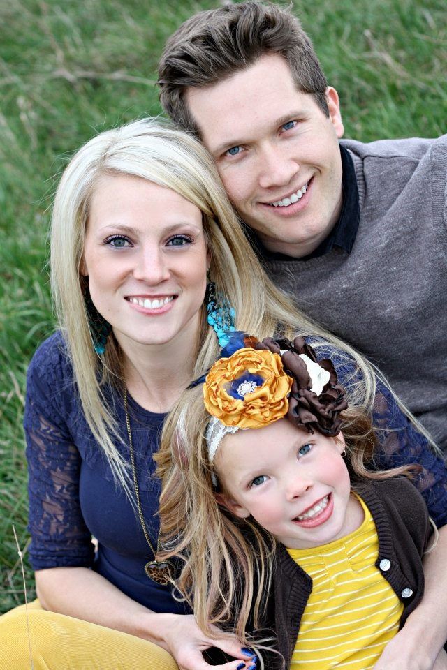 A man and woman are posing for a picture with their daughter.