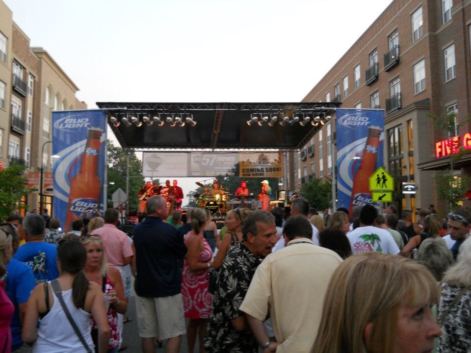 A crowd of people are gathered in front of a stage with coca cola advertisements on it