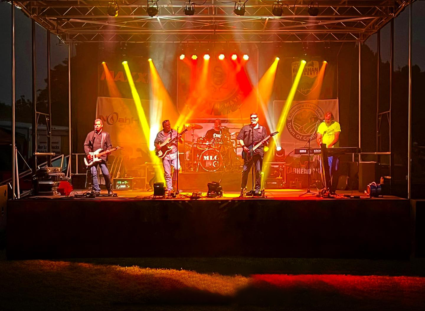 A group of people are playing instruments on a stage at night.