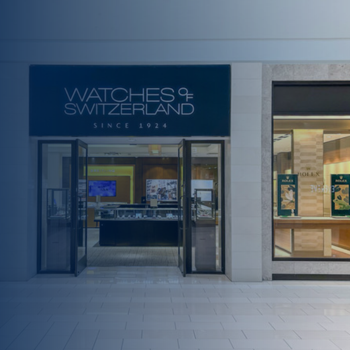 Advertisement for Watches of Switzerland retail transformation with SAP. Storefront view, blue and green color scheme.