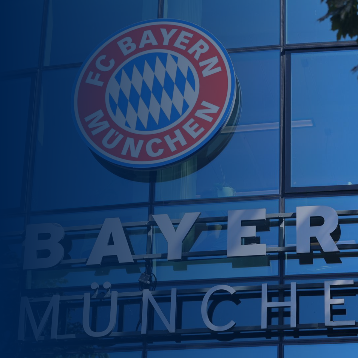 The FC Bayern Munich logo on a building facade; blue and red colors.