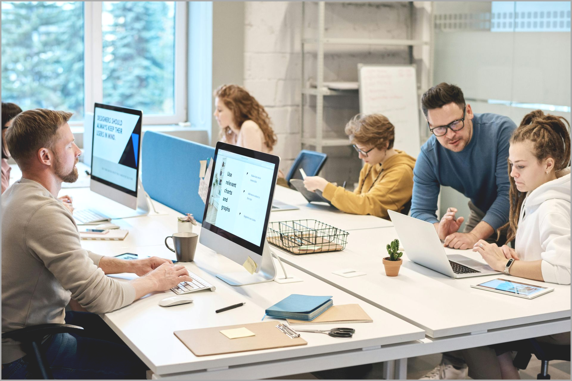 People working at desks in a modern office with computers.
