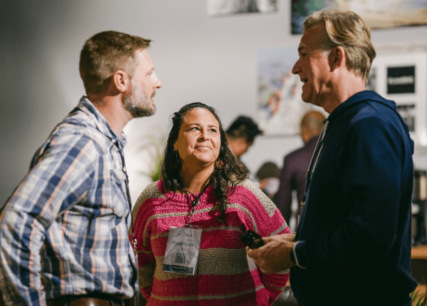 A group of people are standing next to each other and talking in a room.