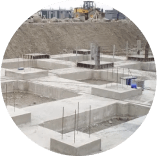 A construction site with concrete foundations and a bulldozer in the background.