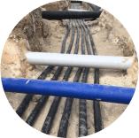A bunch of pipes are laying in the dirt in a circle.